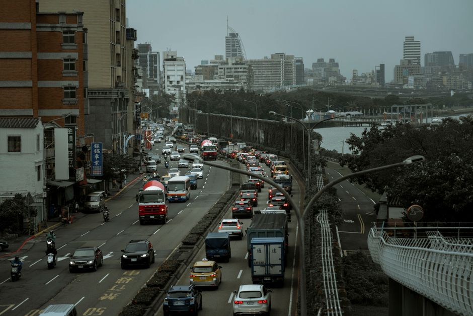 Mobilidade Urbana — A bustling city street filled with cars and trucks in an urban traffic jam during the day.