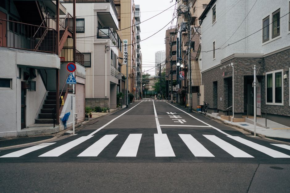 Mobilidade Urbana — Tokyo city street with crosswalk and urban architecture, portraying Tokyo's urban atmosphere.
