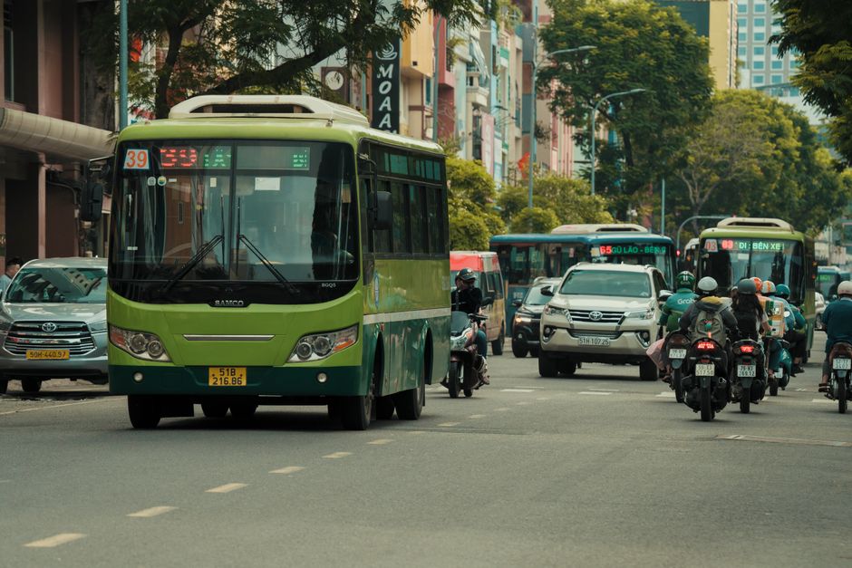Mobilidade Urbana — A bustling urban scene in Vietnam with buses and motorbikes on the city streets.