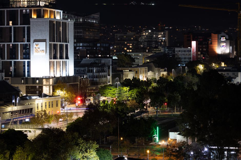 Mobilidade Urbana — Dramatic nighttime view of a cityscape with illuminated buildings and streets, highlighting urban life