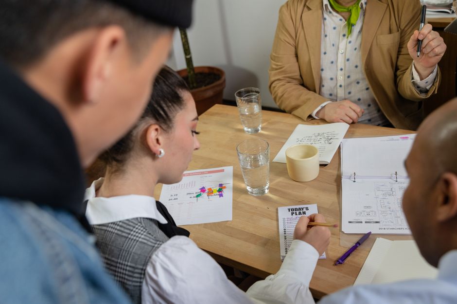 Mobilidade Urbana — Diverse team engaging in a strategic meeting, reviewing plans and documents at a table.
