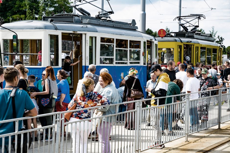 Mobilidade Urbana — Busy tram stop in Wrocław with people boarding vintage and modern trams.