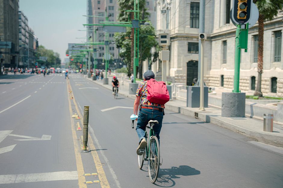 Mobilidade Urbana — Back view of a man cycling on an empty city street on a sunny day.